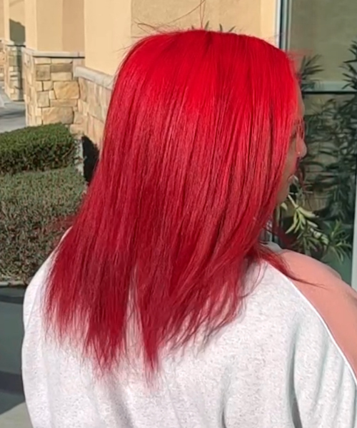 A woman with long red hair standing outside