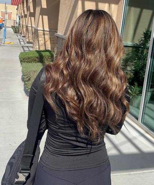 The back of a woman's head as she walks down a sidewalk