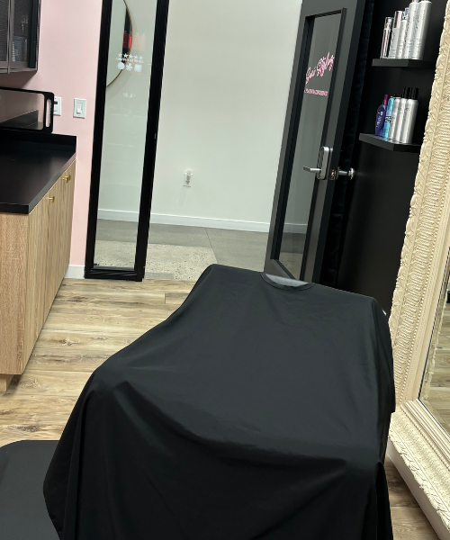 A hair salon with a black chair and a mirror